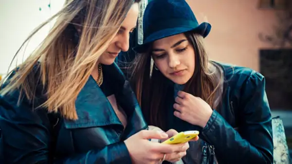 Två vänner som övar portugisiska tittar i en mobil