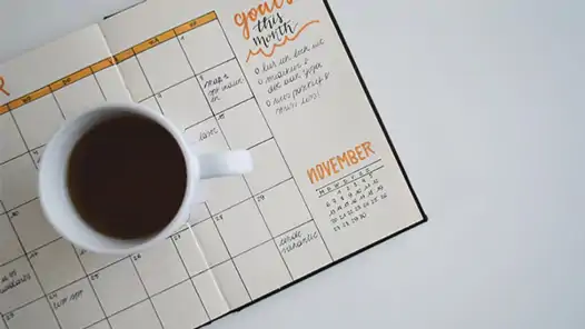 Kaffekopp som står på en uppslagen kalender.