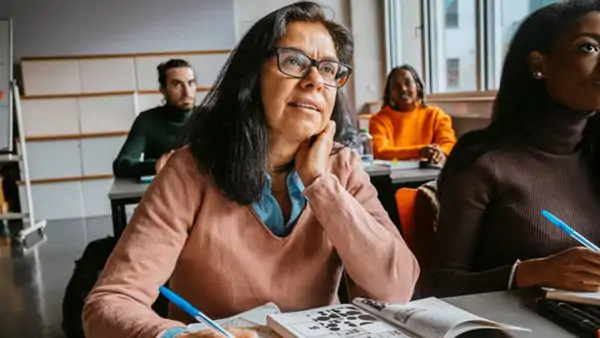 Kvinna som sitter och studerar i ett klassrum med språkundervisning på Folkuniversitetet